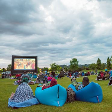 Park visitors enjoy watching an outdoor movie on the big screen.